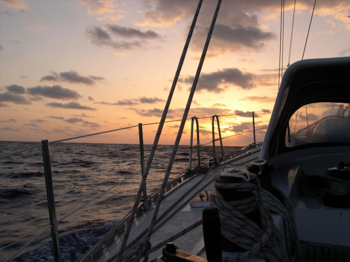 Voilier avançant sur l'océan au coucher du soleil